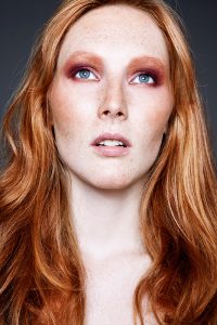 Pink-orange Eyeshadow, blue eyes, red haired model with freckles.